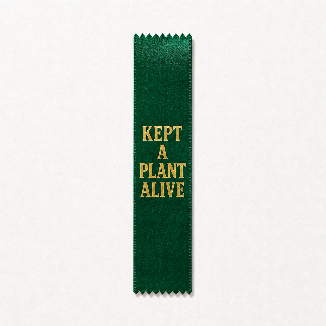 Green gold-foil ribbon saying KEPT A PLANT ALIVE, with pinked zigzag ends; illustrative mockup